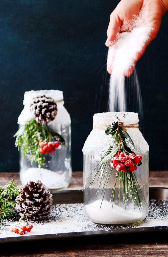 pour salt into snowy DIY mason jar centerpieces with candles
