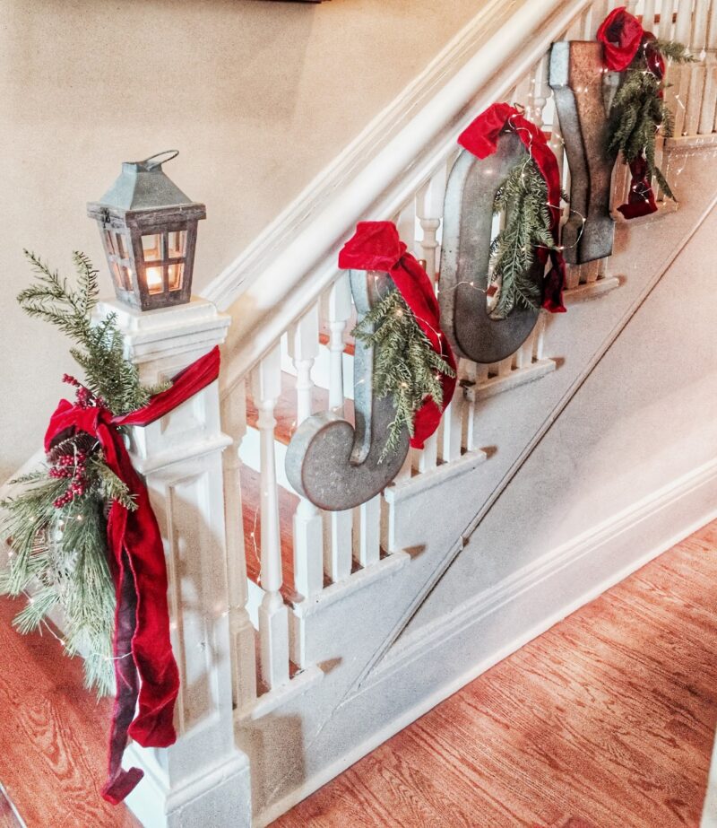use greenery and ribbons to attach Christmas letters to the stair railing