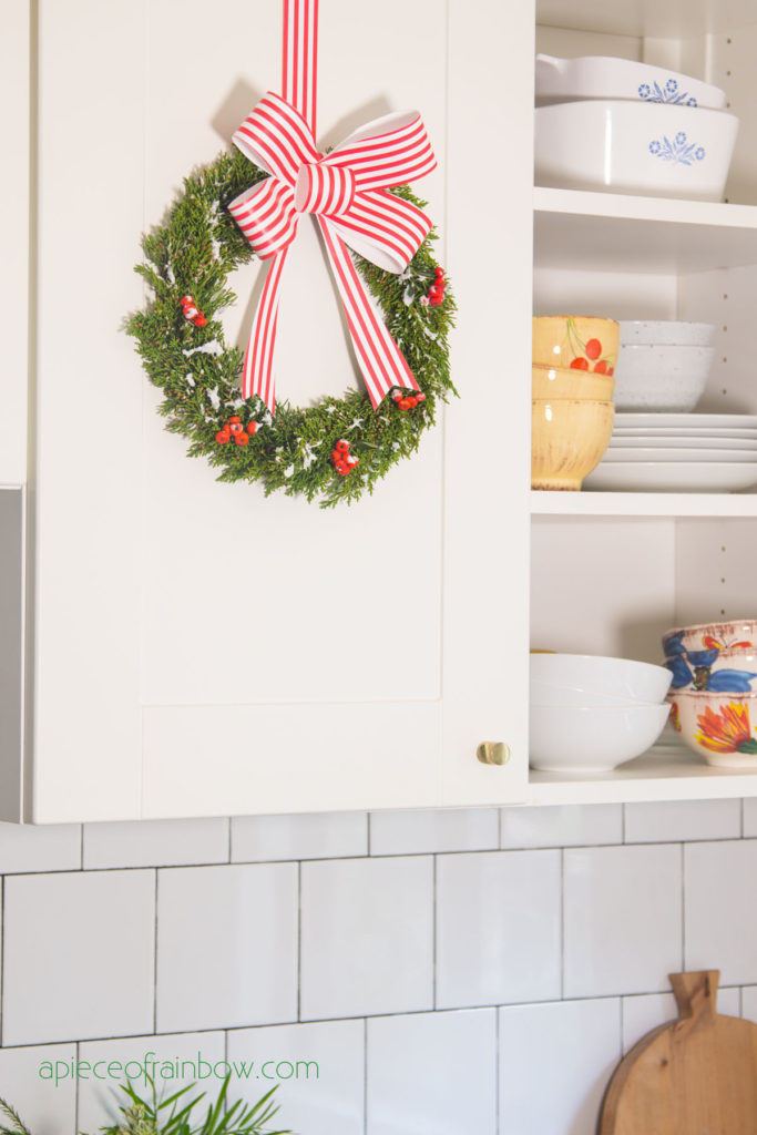 white kitchen cabinet with open shelves and DIY Christmas wreath