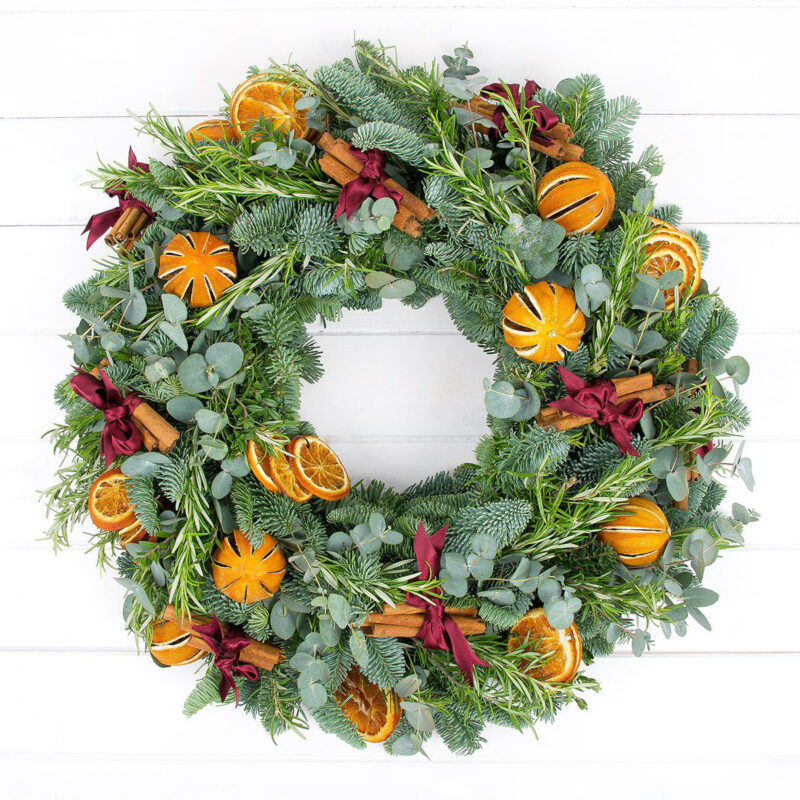 stunning orange Christmas wreath is made with a festive mix of dried orange slices and dried whole oranges, cinnamon sticks, rosemary, spruce, and eucalyptus. 