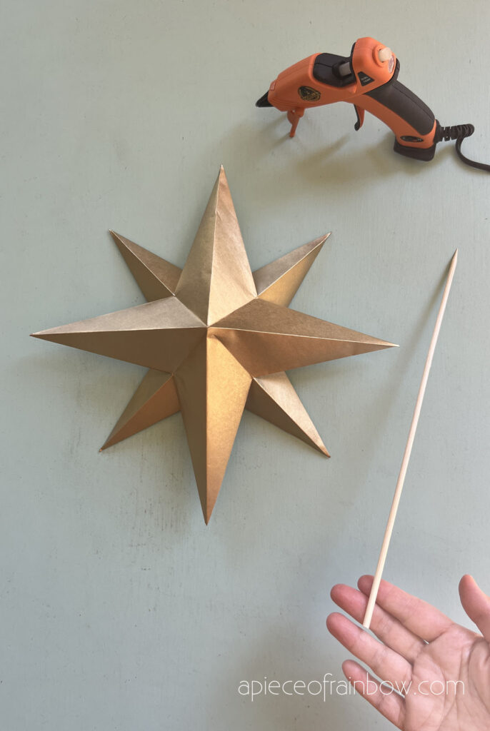 use hot glue to attach a stick or long bamboo skewer to the back of Christmas star tree topper